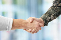 A civilian person and a military member shaking hands